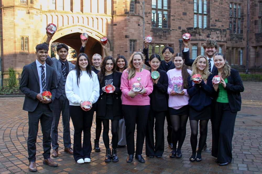 Sixth Form students at Bolton School holding Christmas Puddings