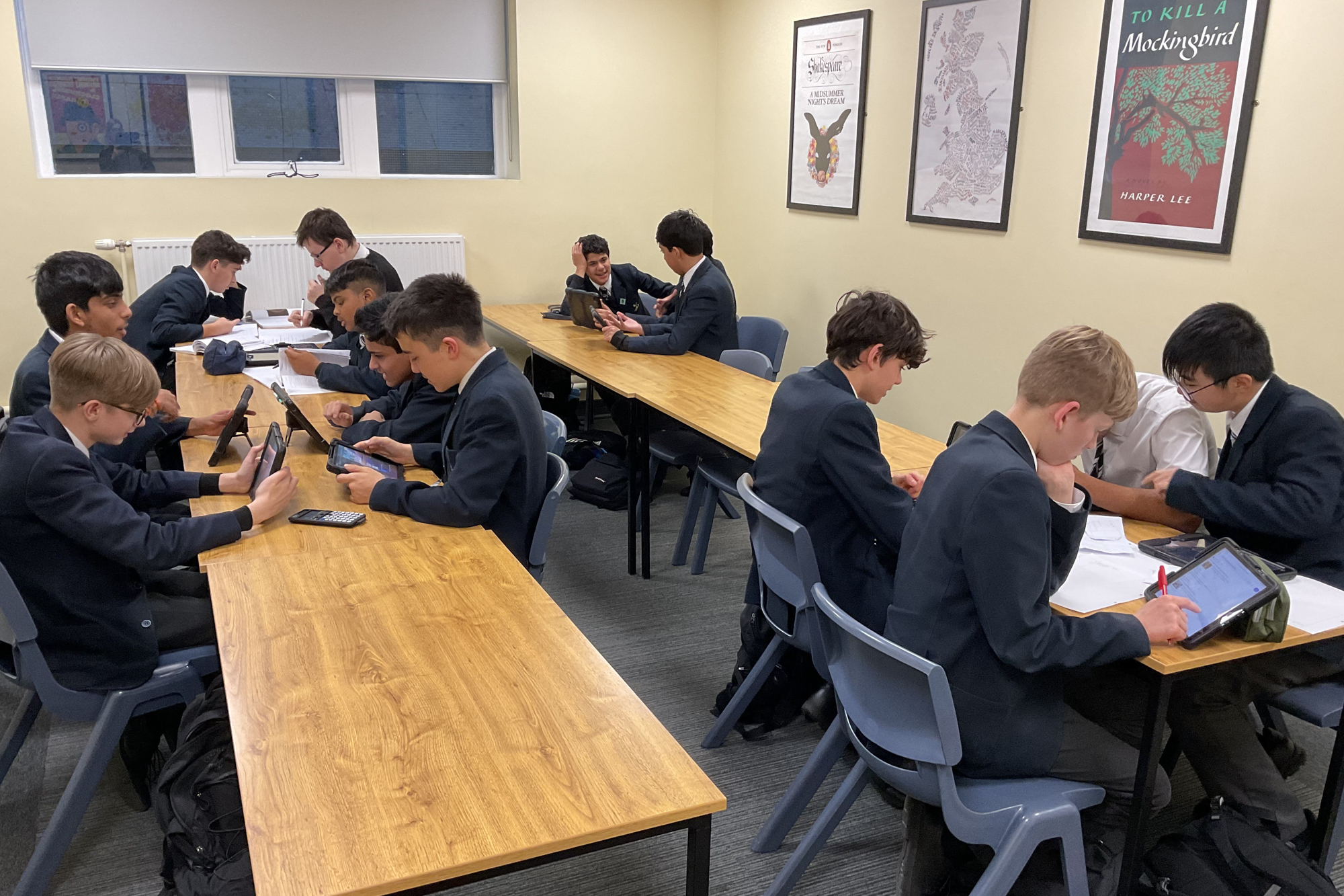 Four groups of Bolton School Boys' Division pupils gathered around tables in a classroom while working together on their iPads