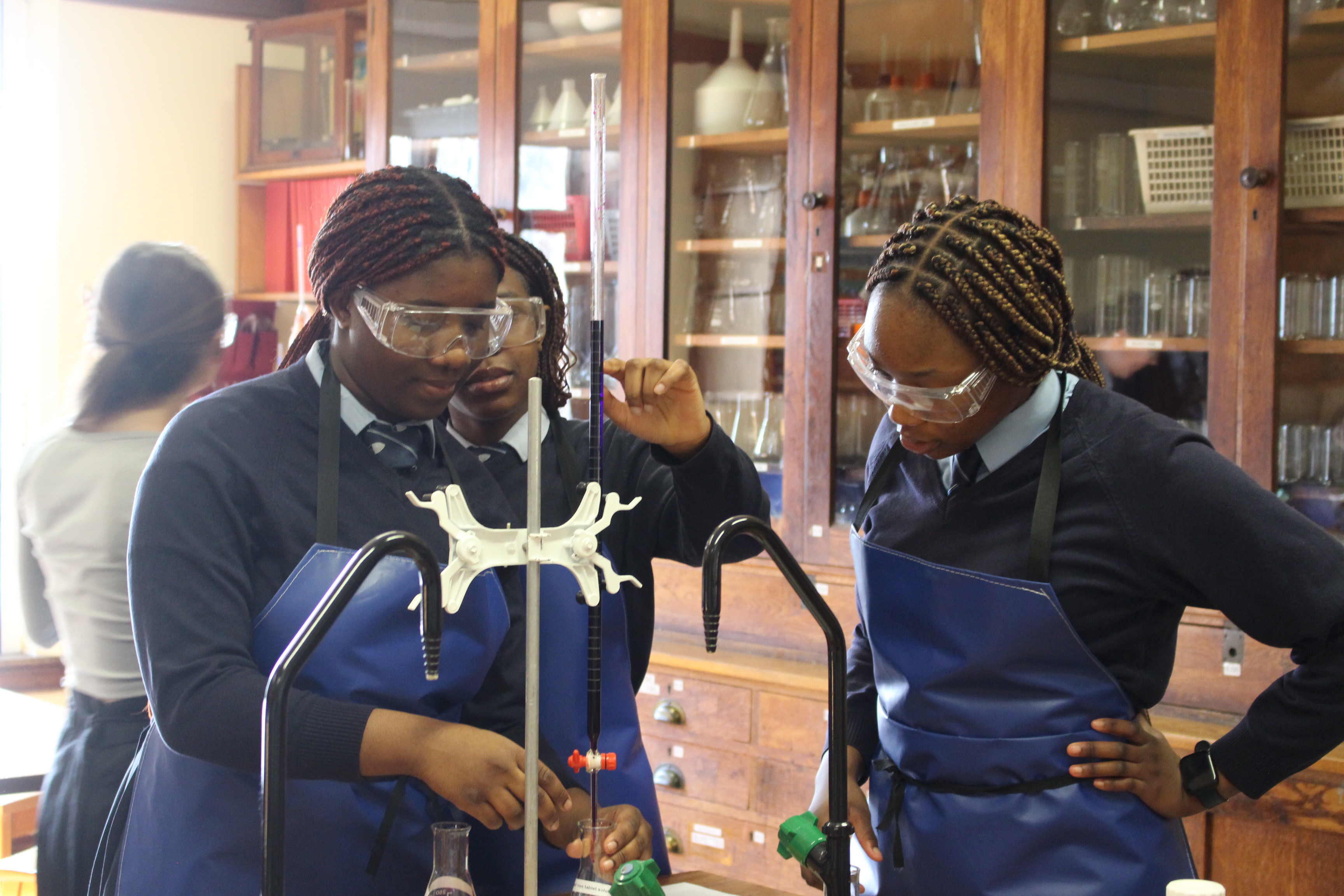 A trio of students conducting a practical science experiment in a laboratory at Bolton School